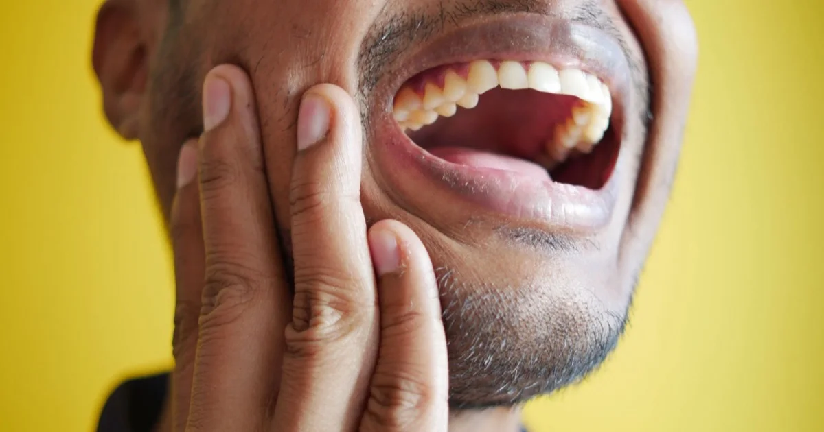 Man holding his cheek — jaw discomfort