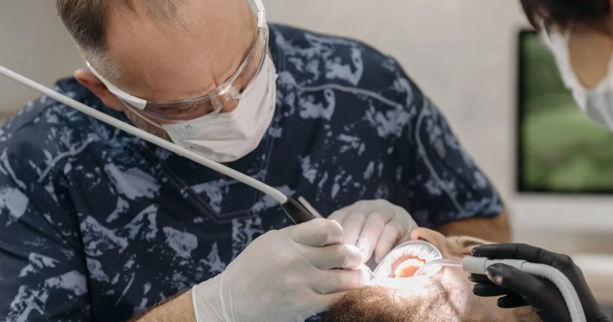 A dentist examining a patient's teeth with instruments